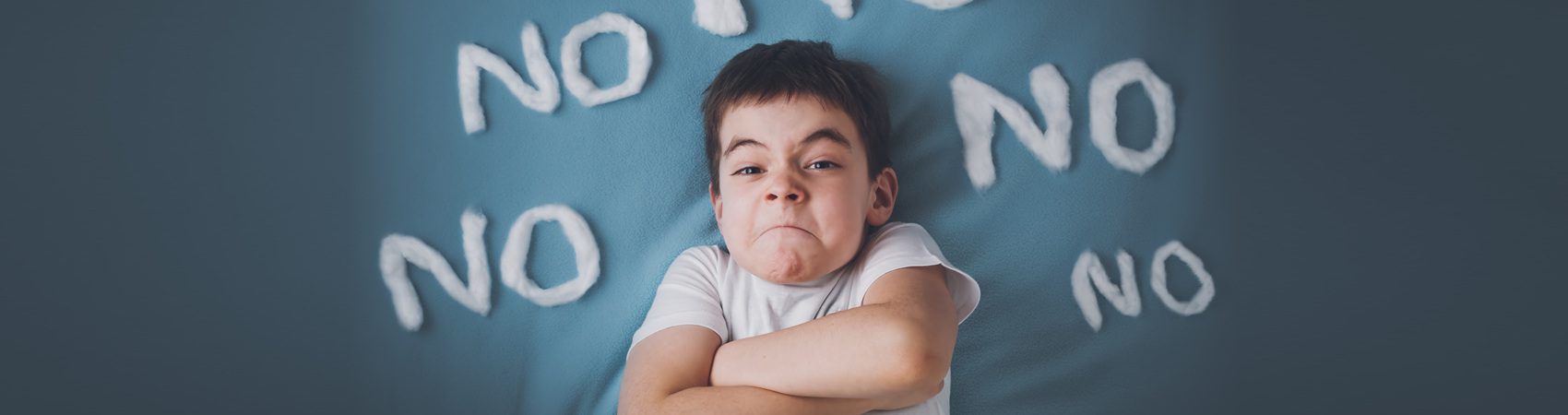 Bad boy on blue blanket background. Angry child with no words around.